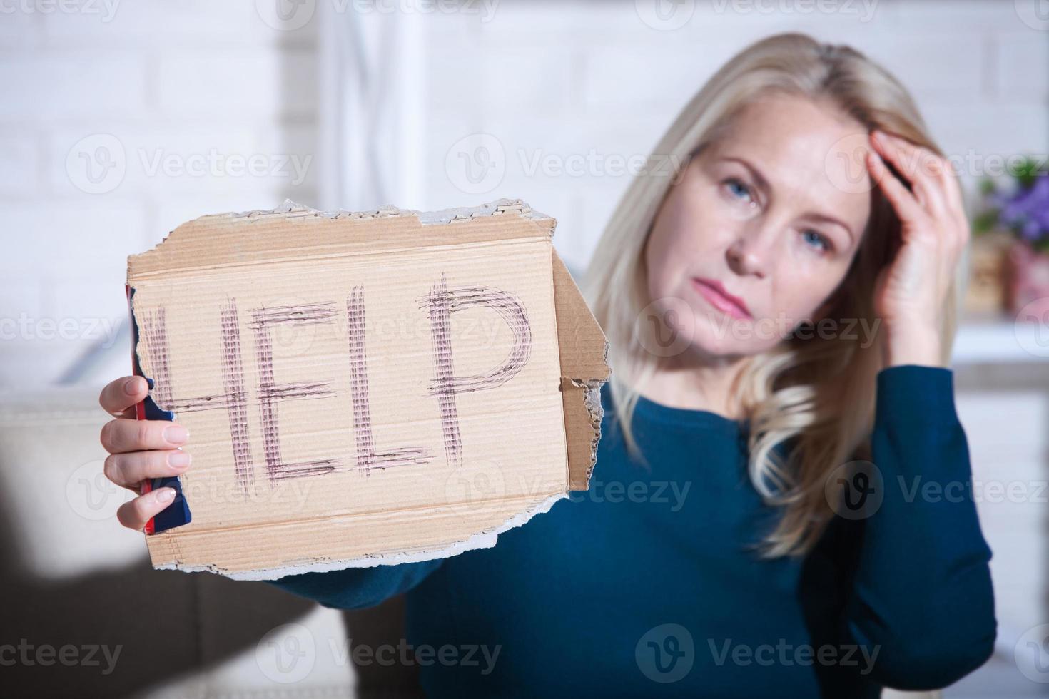 Woman alcoholic social problems concept sitting asking for help. Middle aged woman holding a sign m asking for help. photo