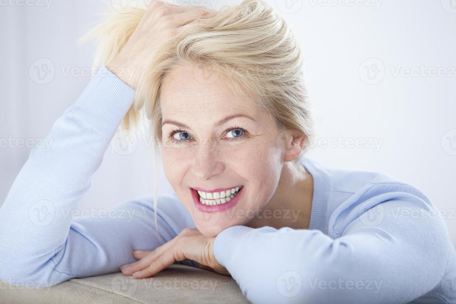 Active beautiful middle-aged woman smiling friendly and looking in camera. Woman's face closeup. Realistic images without retouching with their own imperfections. Selective focus. photo