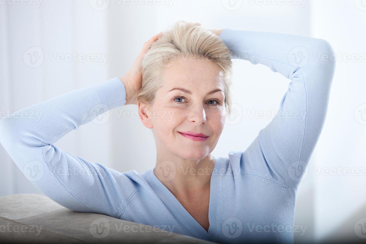Active beautiful middle-aged woman smiling friendly and looking in camera. Woman's face closeup. Realistic images without retouching with their own imperfections. Selective focus. photo
