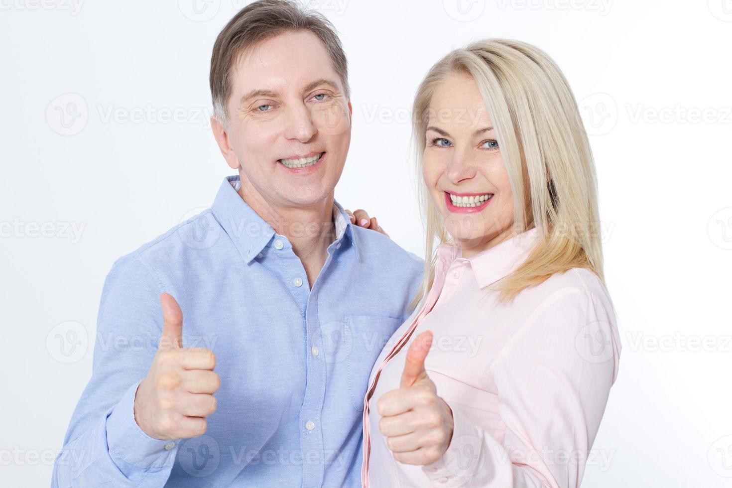 Happy middle aged couple in embraces and show thumb up. photo