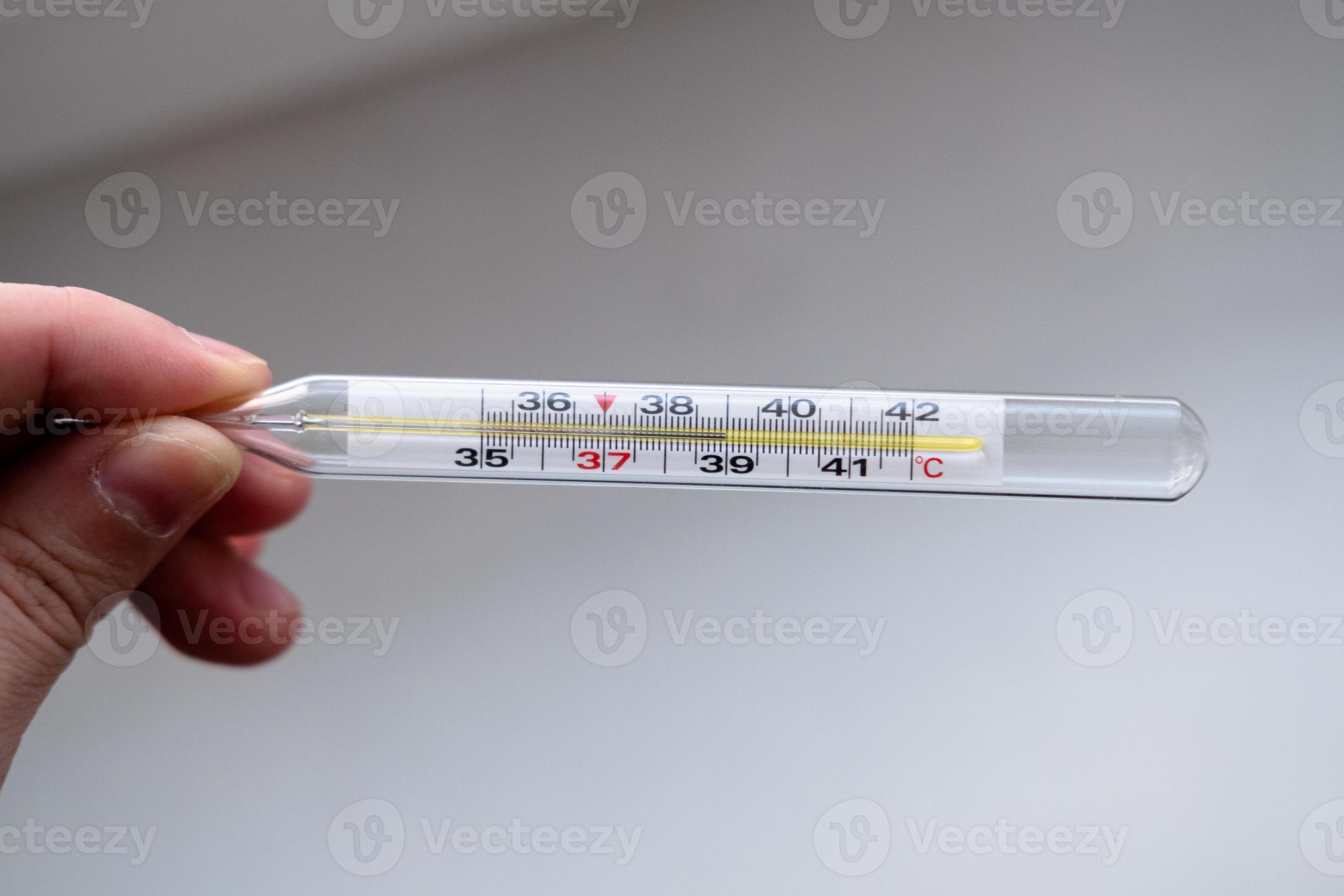 mercury thermometer with a temperature of 39 in the hands on a white
