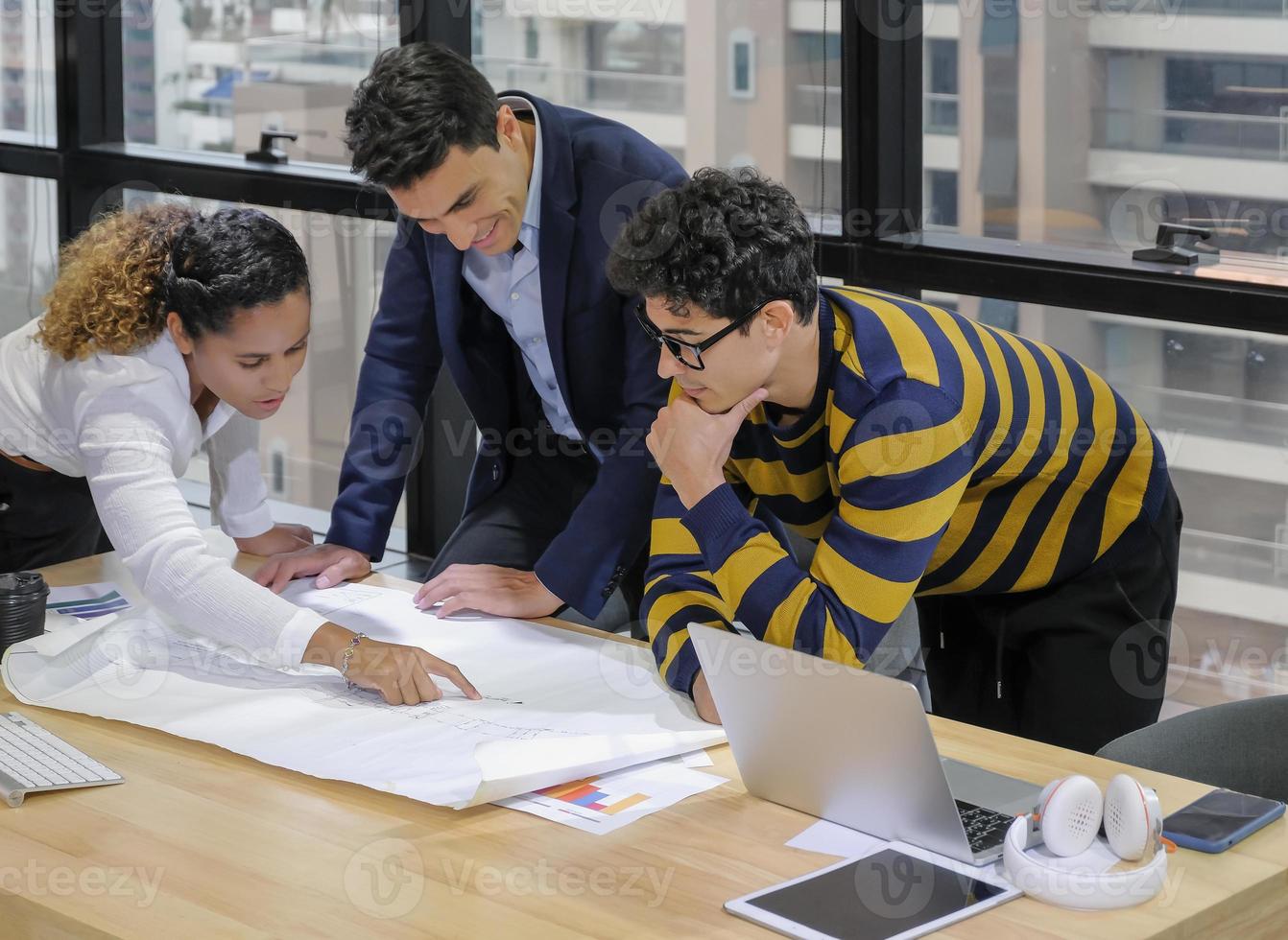 el equipo de diseñadores de negocios de diversidad étnica está trabajando juntos en el plano en el espacio de oficina moderno con computadora portátil y papeleo en el escritorio. foto