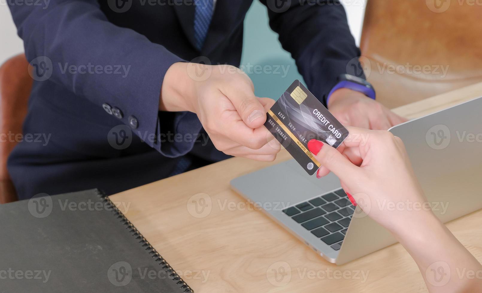 Asian middle-aged male counter service staff receiving a mock up credit card from young female customer for making payments. Service business concept. photo