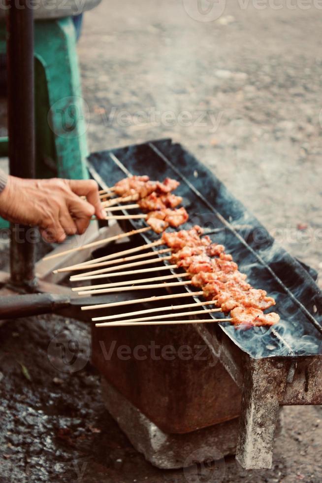 Photo of a satay being grilled on a grill in a market area in Bali.
