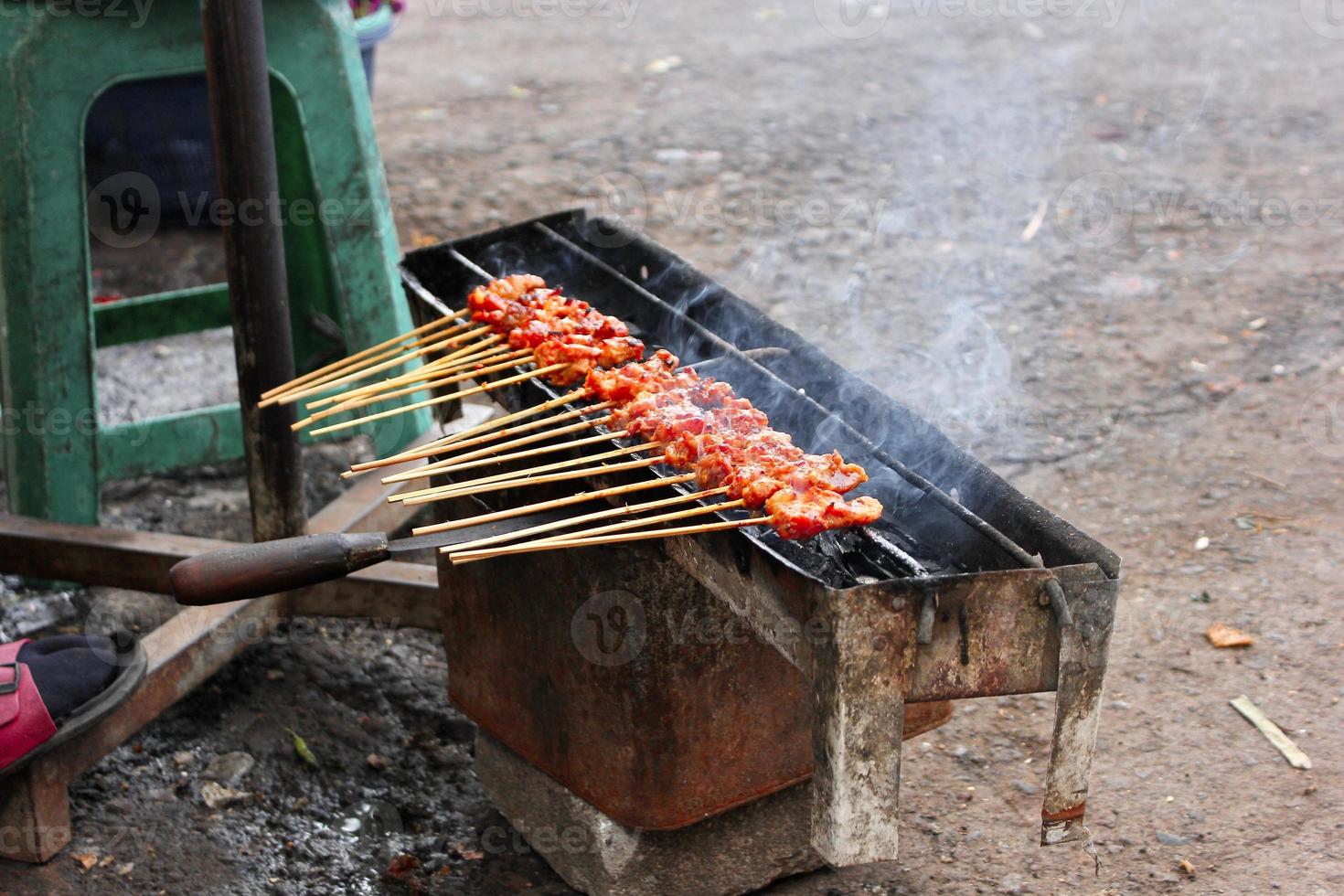 Photo of a satay being grilled on a grill in a market area in Bali.