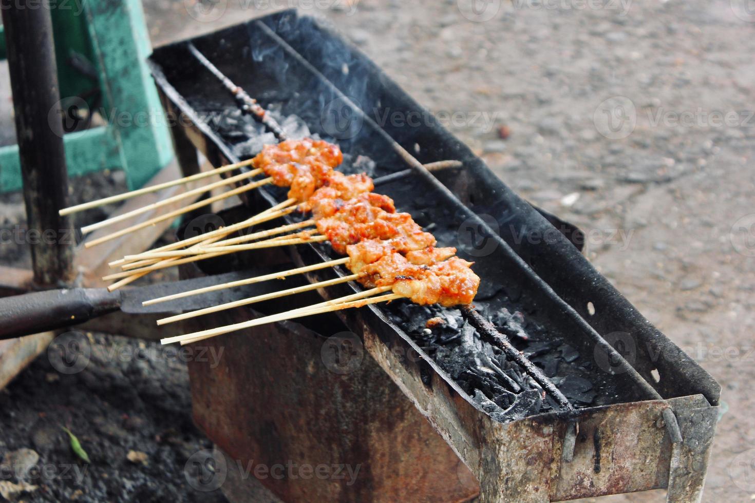 Photo of a satay being grilled on a grill in a market area in Bali.