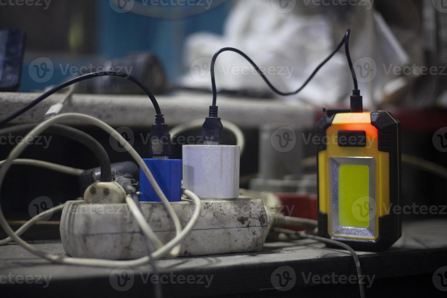 The charger is plugged in. Entangled wires from sockets of various devices. Chaos in home wired equipment. High voltage in the network. photo