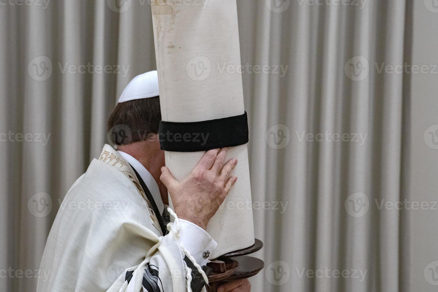 rabino sosteniendo el libro de desplazamiento de la torá de cerca foto