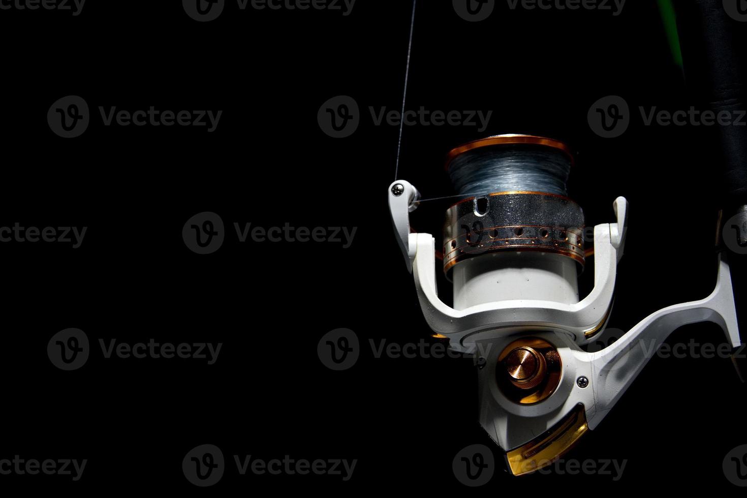 Fishing reel tackle isolated on black photo