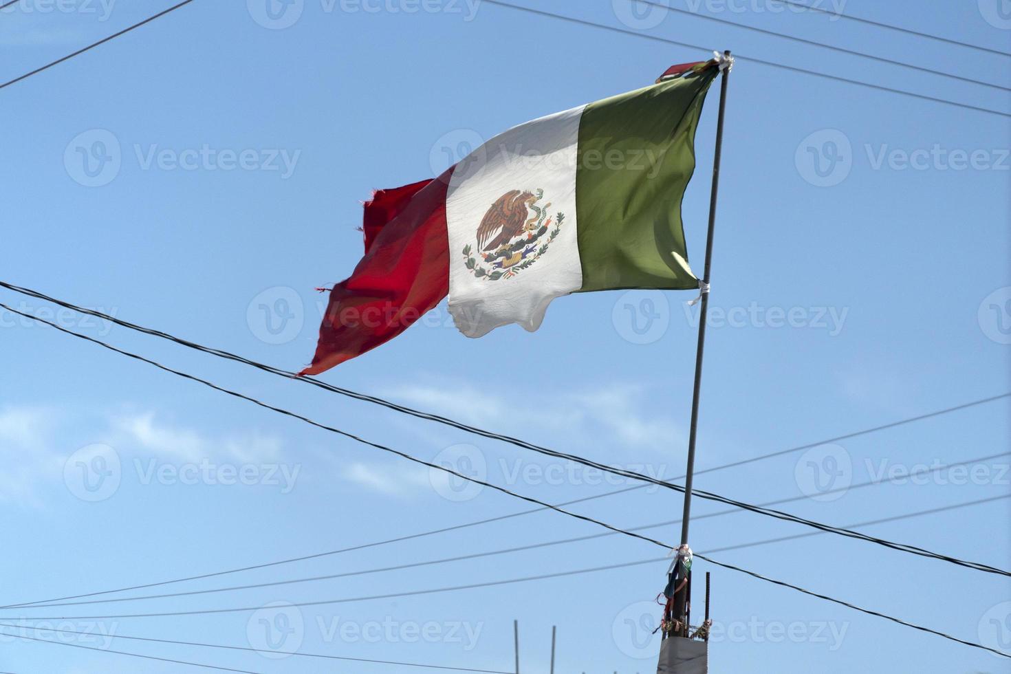 bandera mexicana rota ondeando entre cables foto