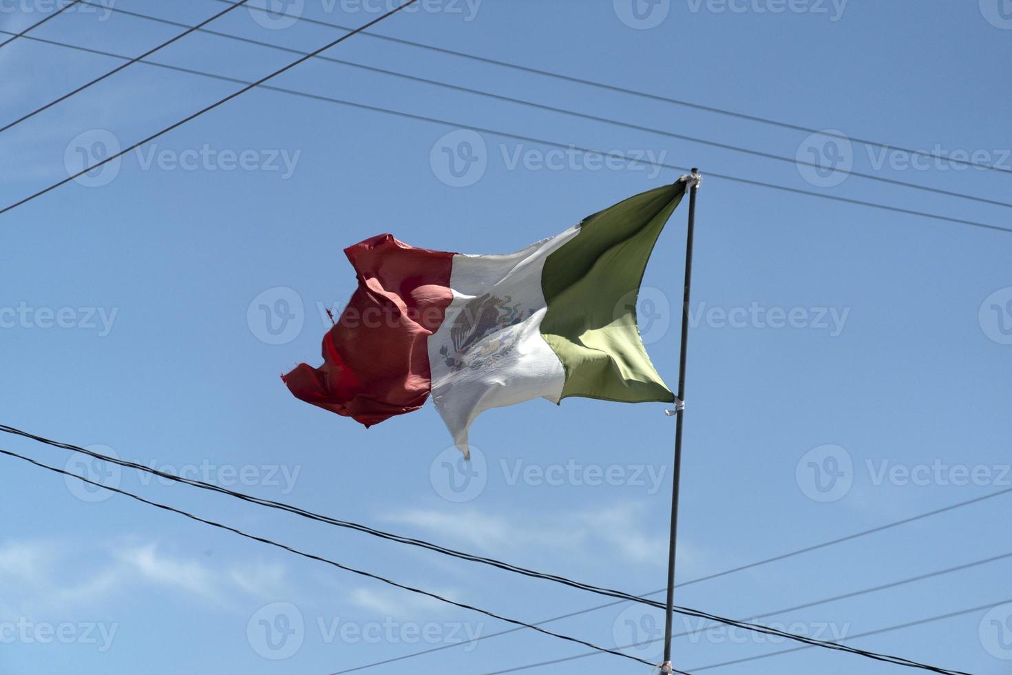 torn mexican flag waving between wires photo