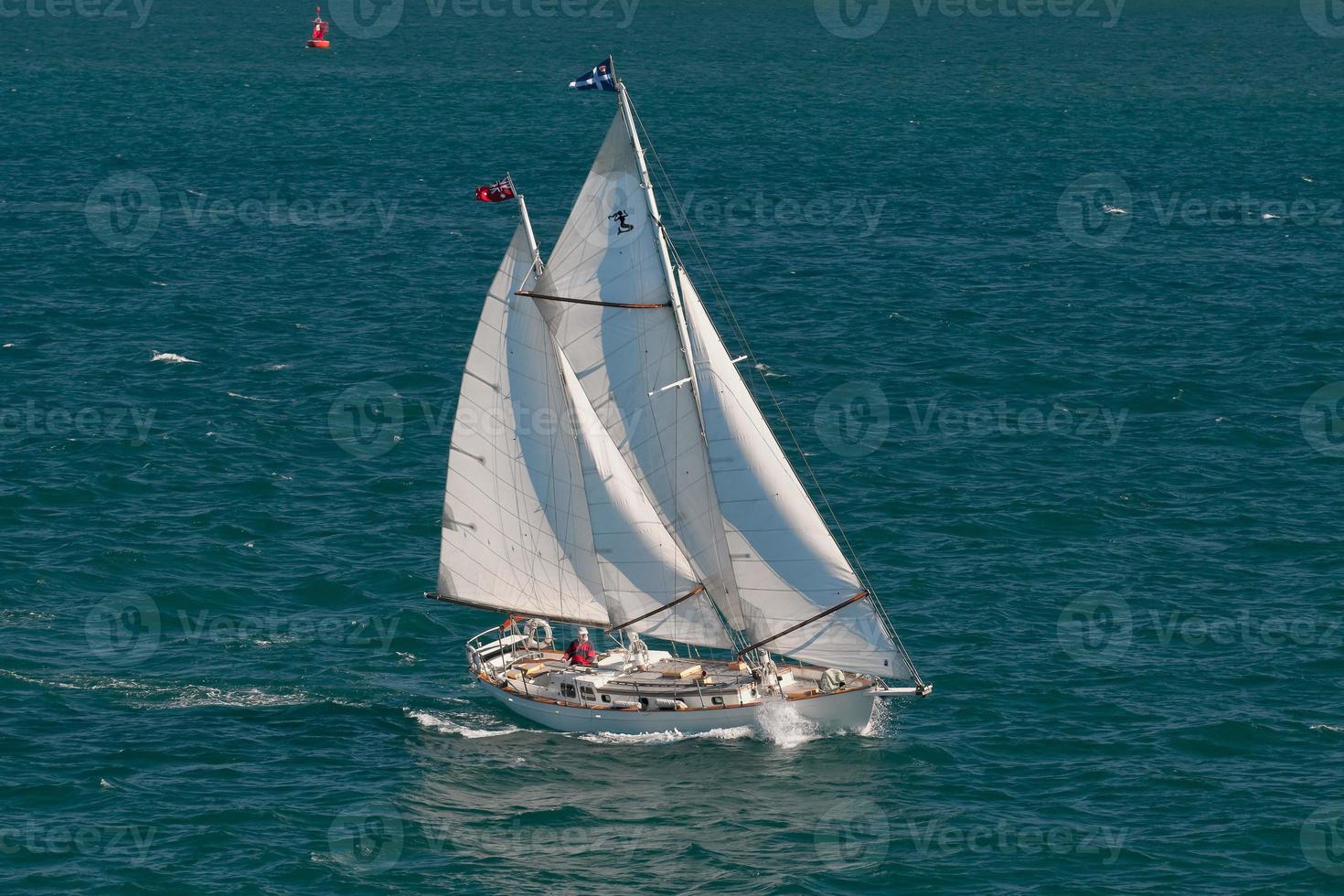 un barco con un capitán solitario navegando en el mar azul foto