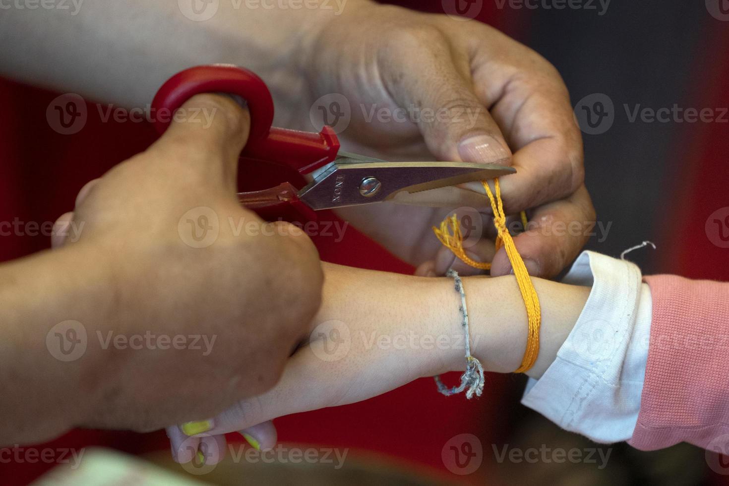 Tibetan monk while putting bracelet on buddihst hand photo