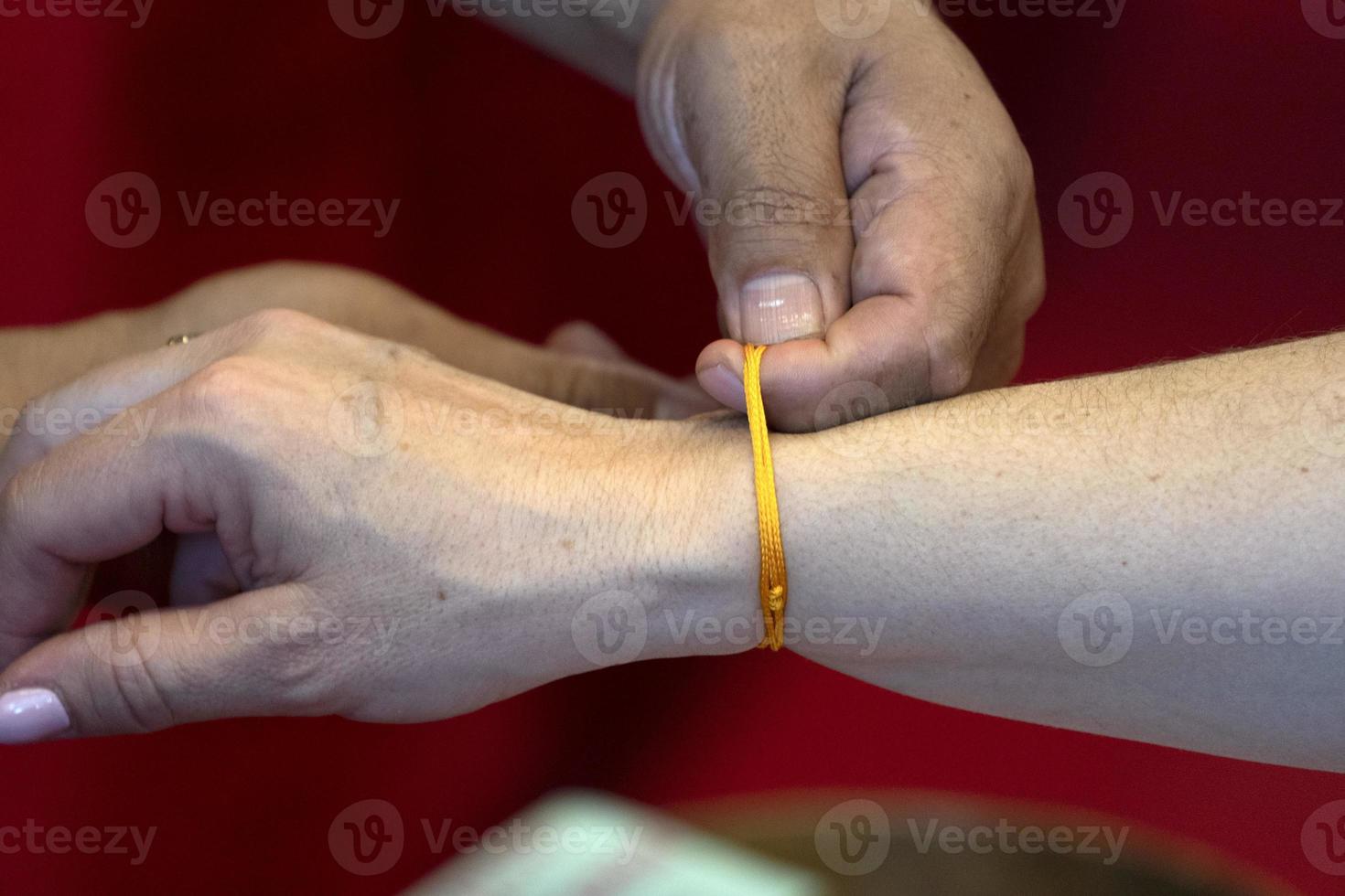 Tibetan monk while putting bracelet on buddihst hand photo