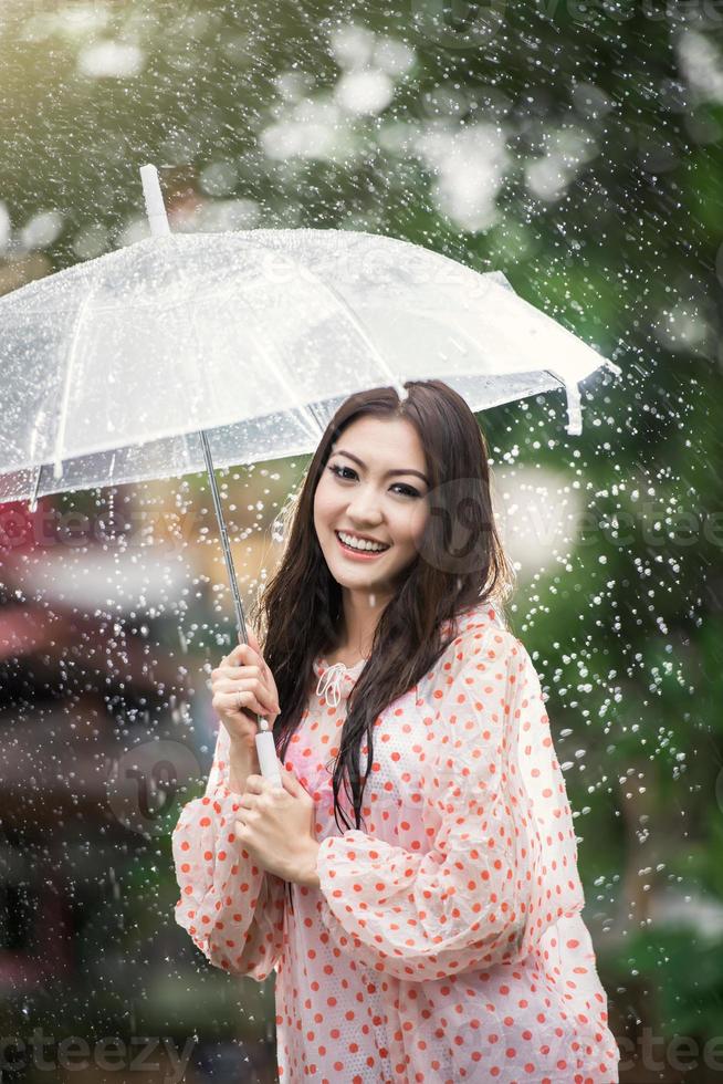 hermosa chica bajo la lluvia con paraguas transparente foto