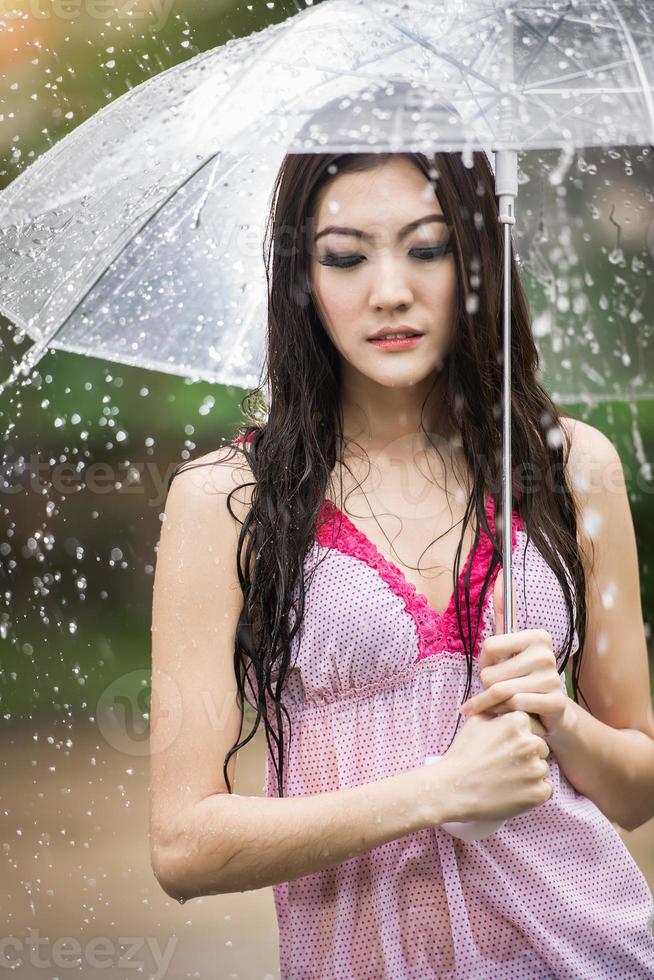 Beautiful girl in the rain with transparent umbrella photo