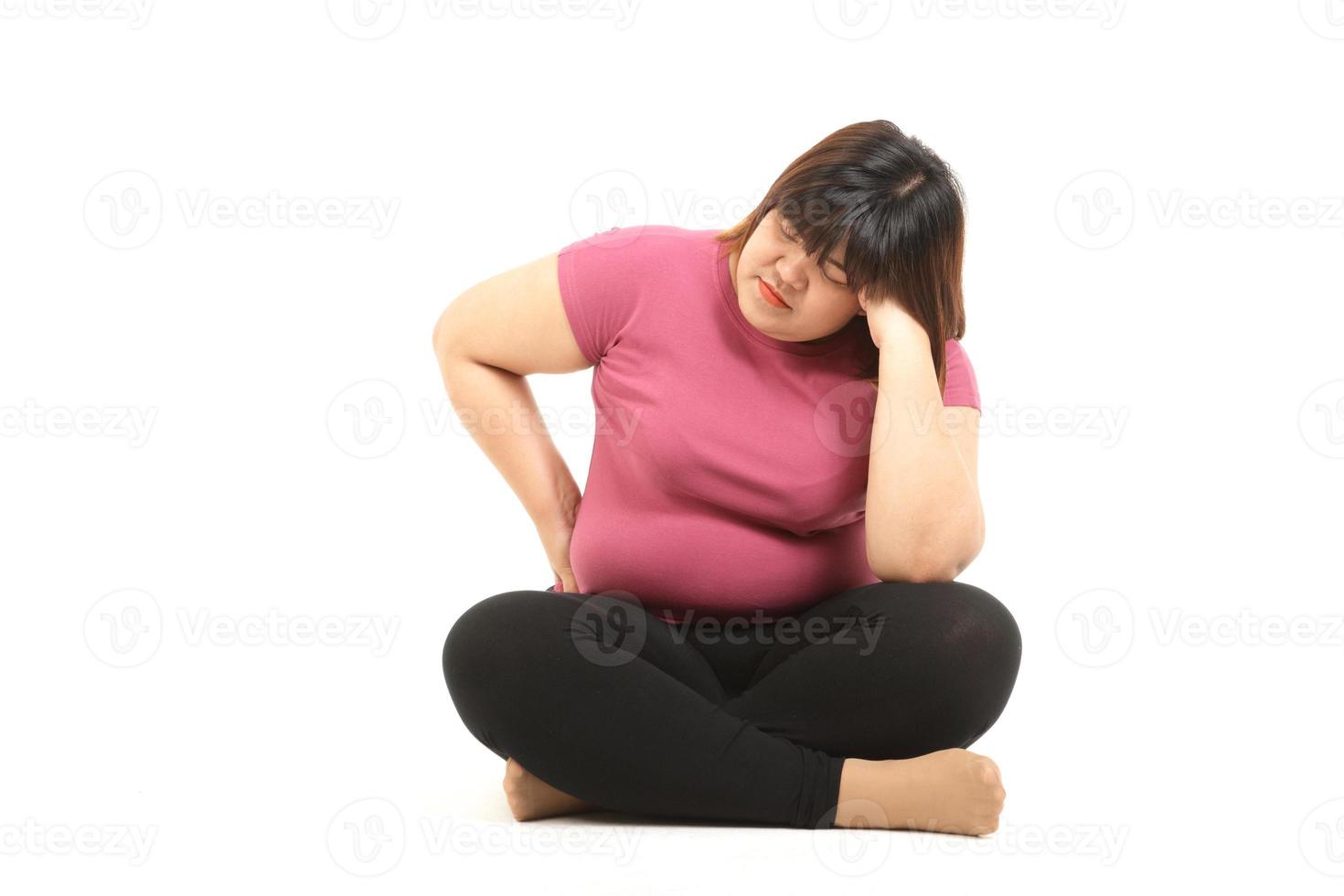mujer asiática gorda con ropa de gimnasia sentada estresada en un fondo blanco. el concepto de perder peso, quemar grasa, hacer ejercicio para mantenerse saludable, problemas de salud de las personas obesas. foto