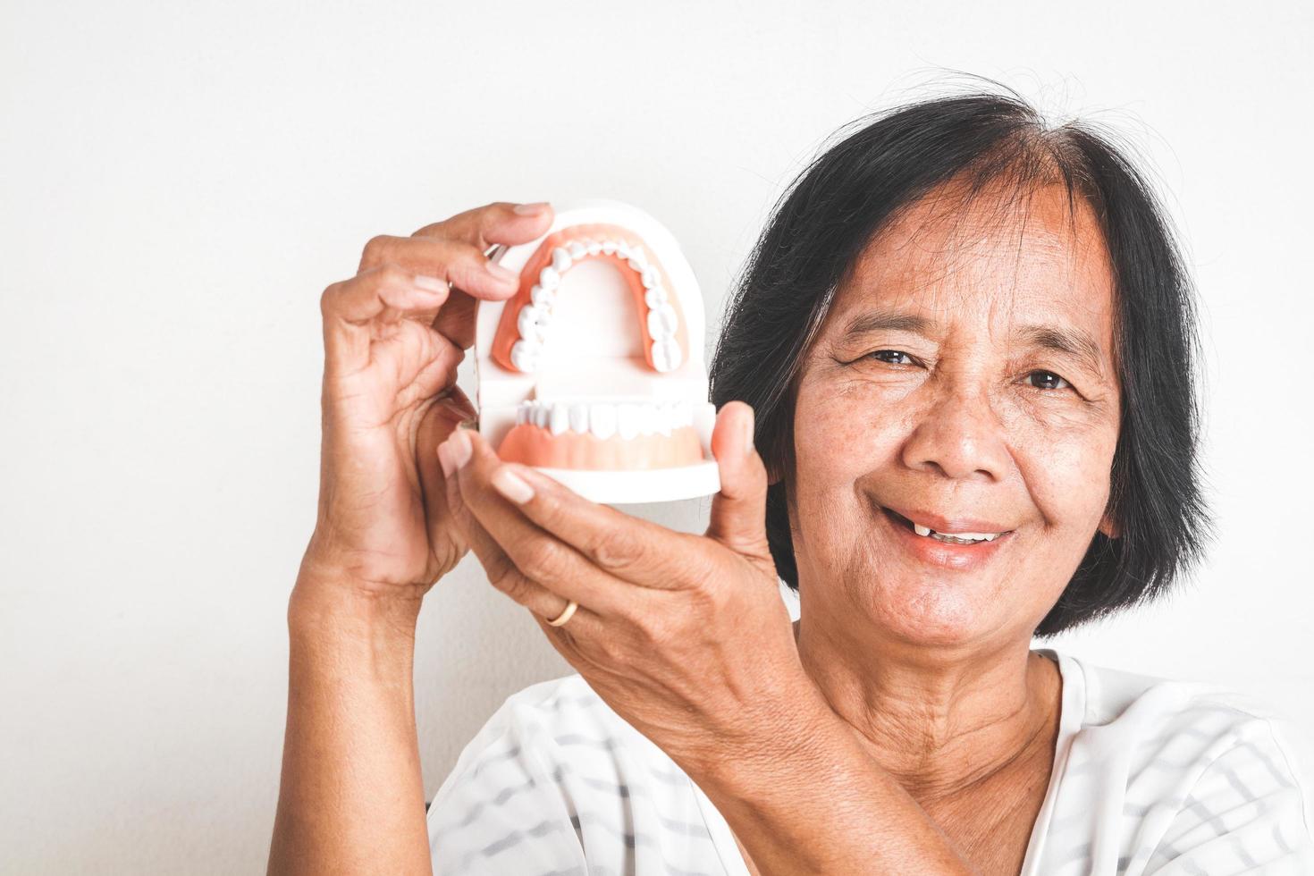 The elderly Asian women hold denture models. Concepts of senior oral health problems and dental care photo