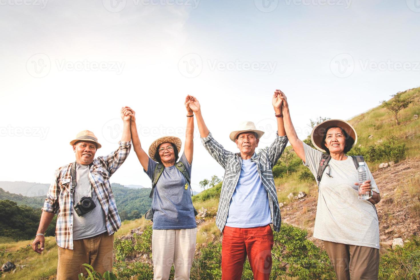 A group of Asian seniors hiking and standing on high mountains enjoying nature. Senior community concepts photo