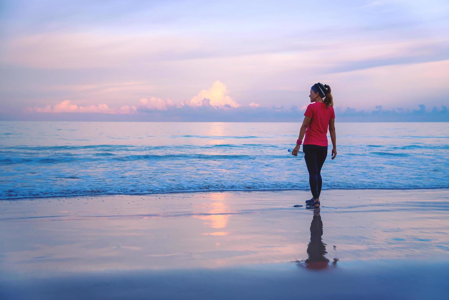 Girl running workout jogging on the beach in the morning. relax and happy with running on the sea. in summer photo