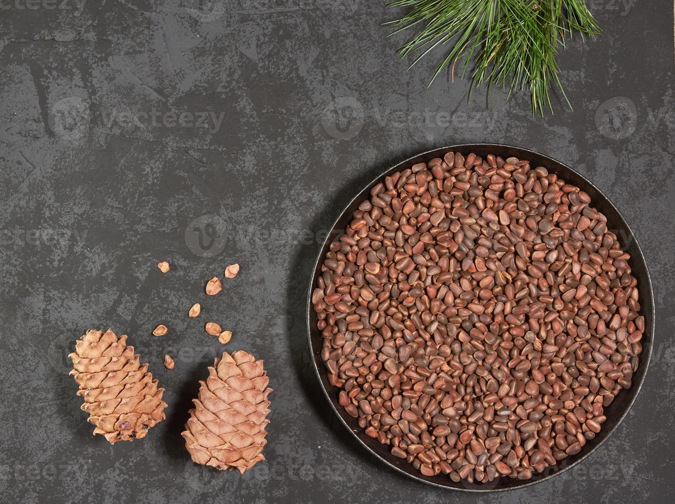 Pine cones and nuts in a frying pan on a dark background with space for copying photo