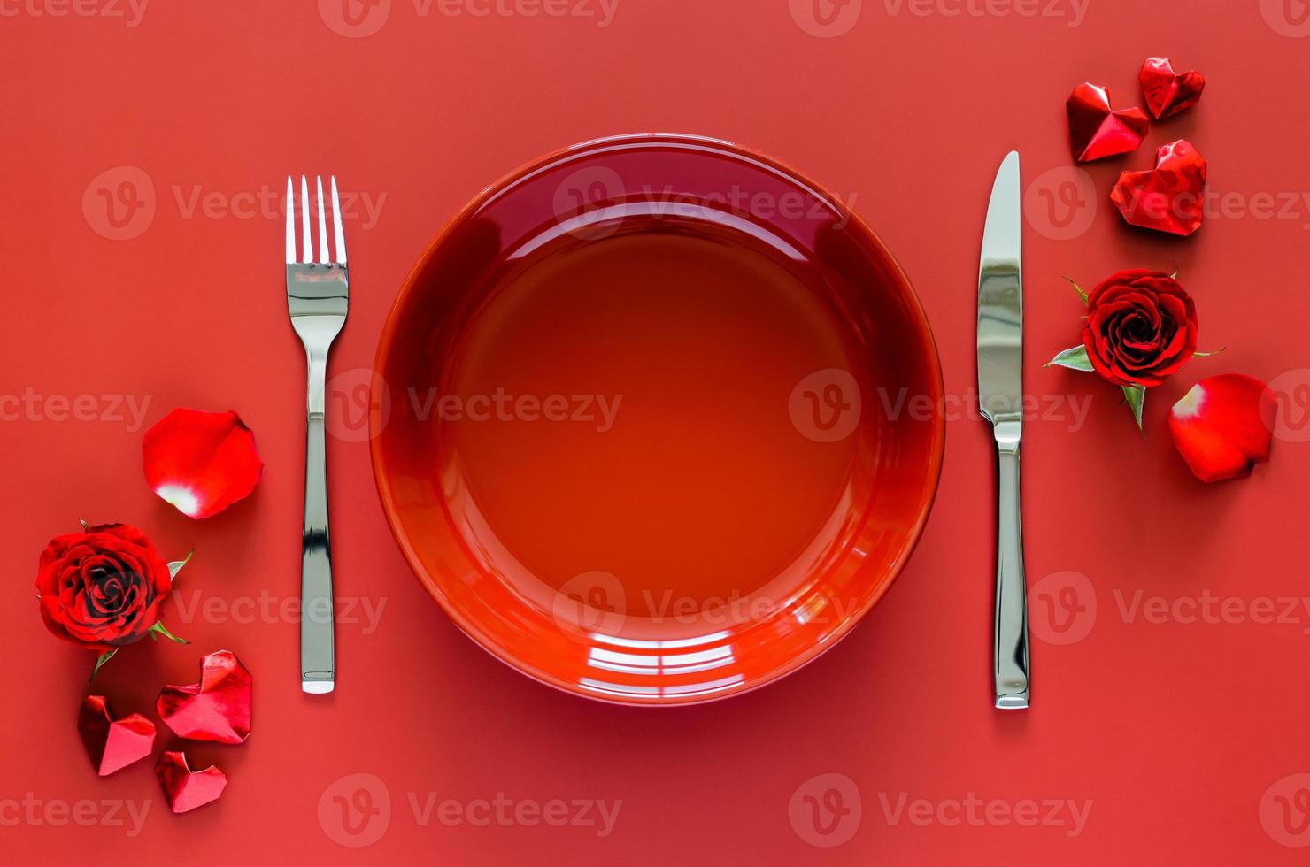 Valentines dining concept with red plate, fork and knife put on red table with rose and love shape paper fold. photo