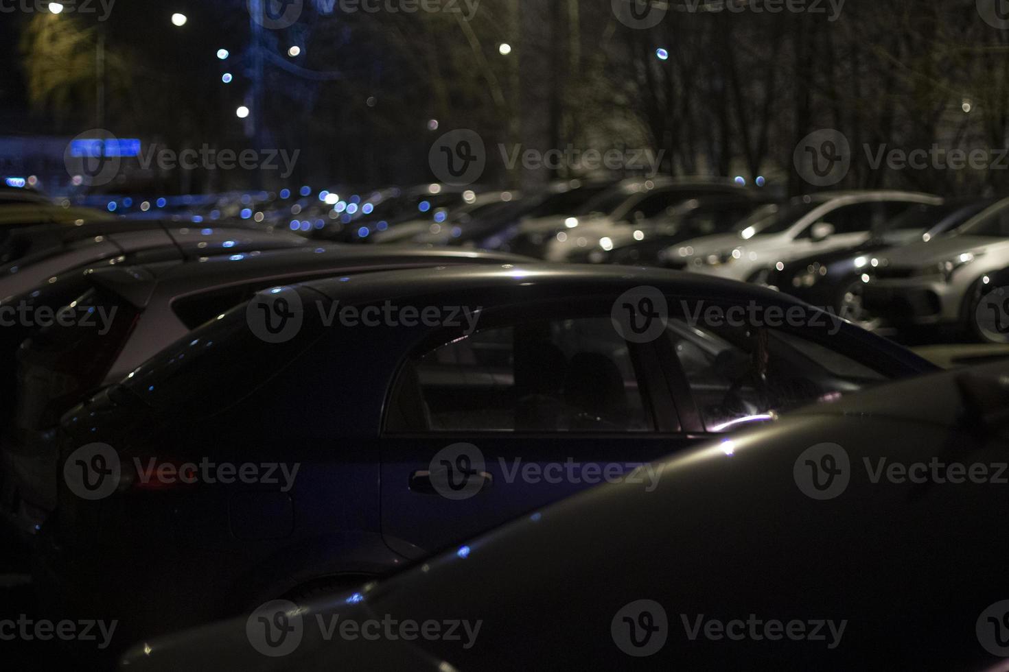 Cars at night in parking lot. Transport in dark. Cars stand in row in street light. photo
