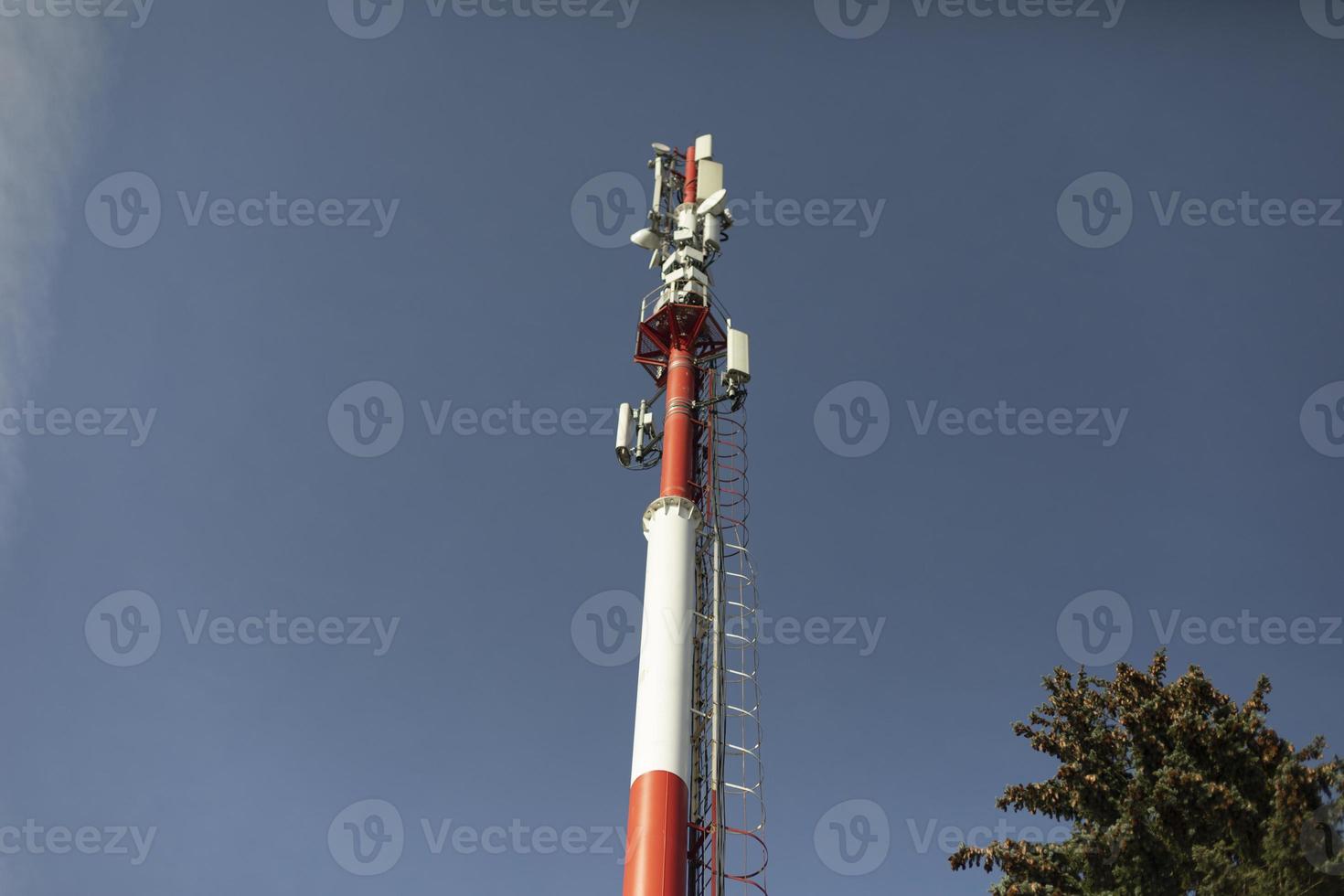 Red pipe against sky. Industrial pipe factory. Boiler station. Communication equipment on pole. Technological object. photo