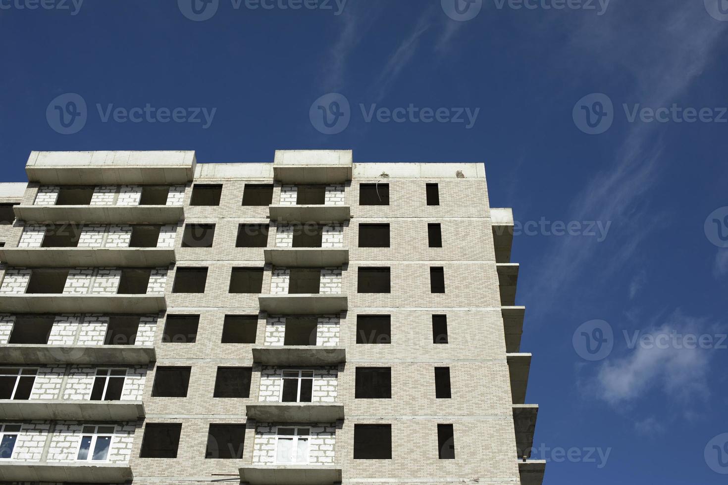 New building. Empty windows in house. Concrete blocks. Buildings in city. photo
