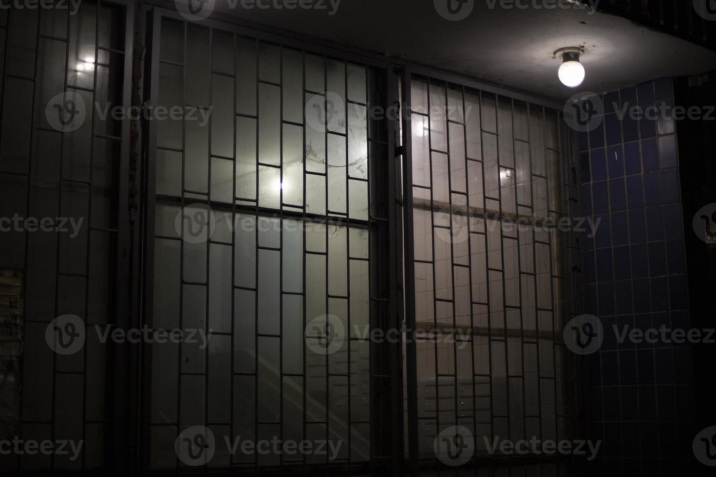Grille on window at night. Window with lattice. Entrance to entrance in evening. photo