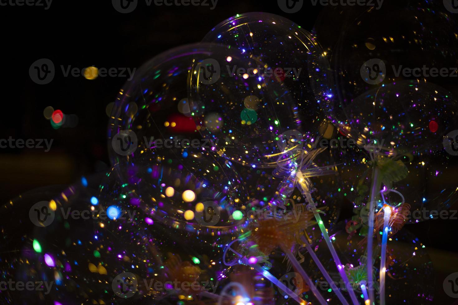 Colored balls with light bulbs inside on dark background. Texture of lights in dark. Details of holiday. Christmas decoration. photo