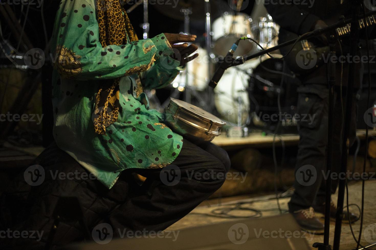 African plays drum. Reggae band performance. Playing there. Details of performance on stage. photo