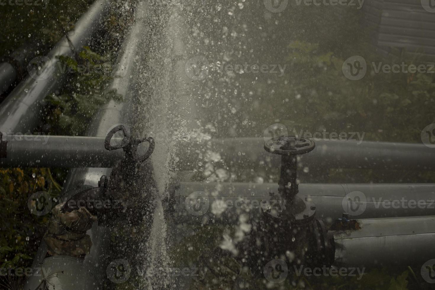 Water pouring out of broken pipe. Pipeline breakthrough. Boiler station accident. photo