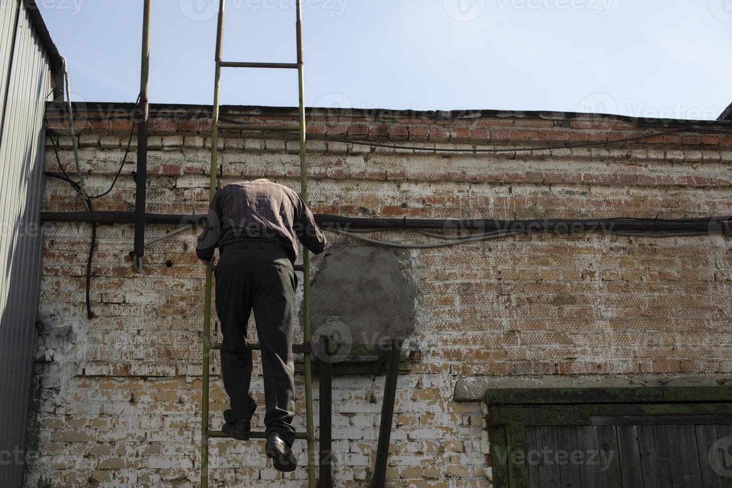 Man climbs ladder onto roof. Person climbs up stairs. Descent from roof. photo