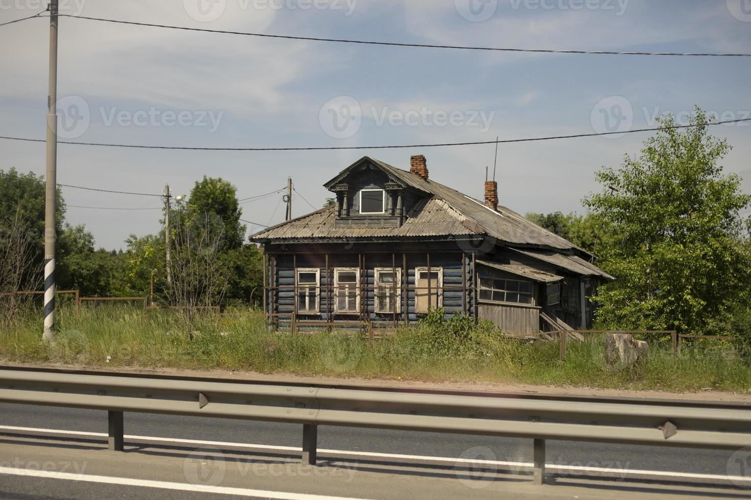 Old house by road. Wooden house in summer. Village in Russia. photo