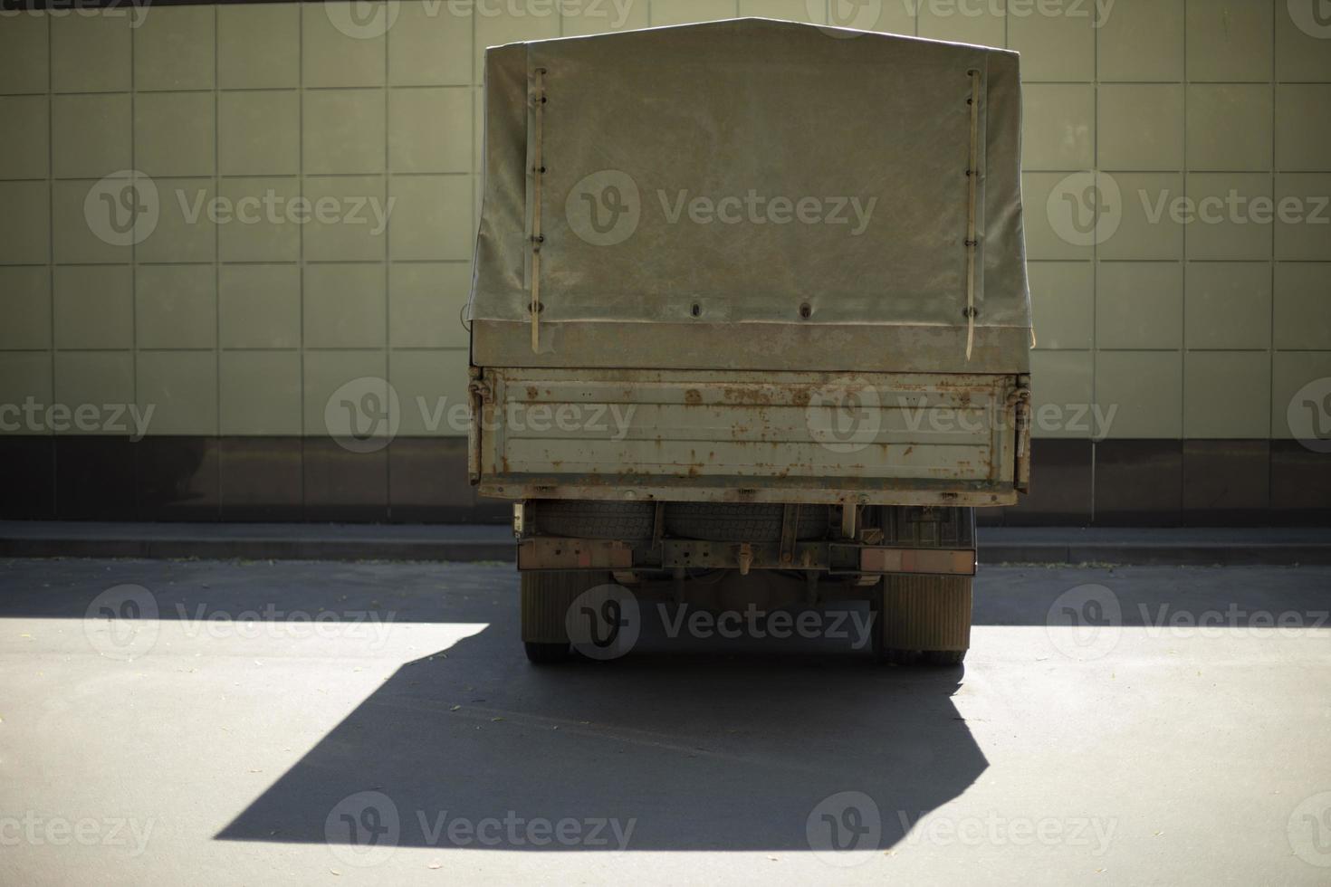 Truck in parking lot. Truck stands near building. Car is waiting to load. photo