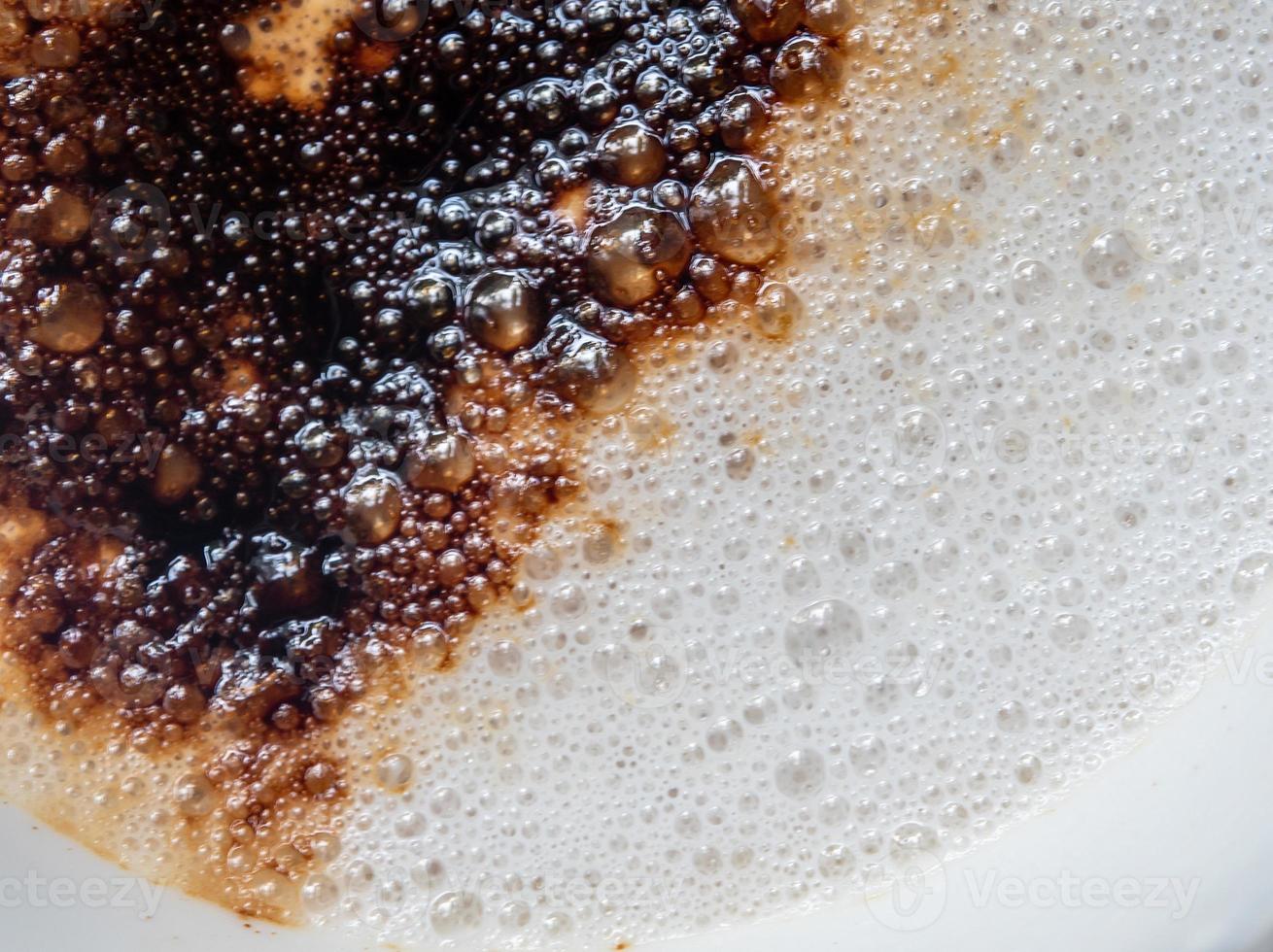 espuma de leche blanca suave en una taza de café y el color marrón oscuro del café en polvo rociado sobre ella foto