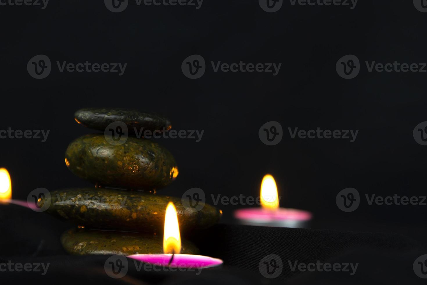 Layers of stones are on dark background, two rounded candles, use for massage and yoga obect concept photo