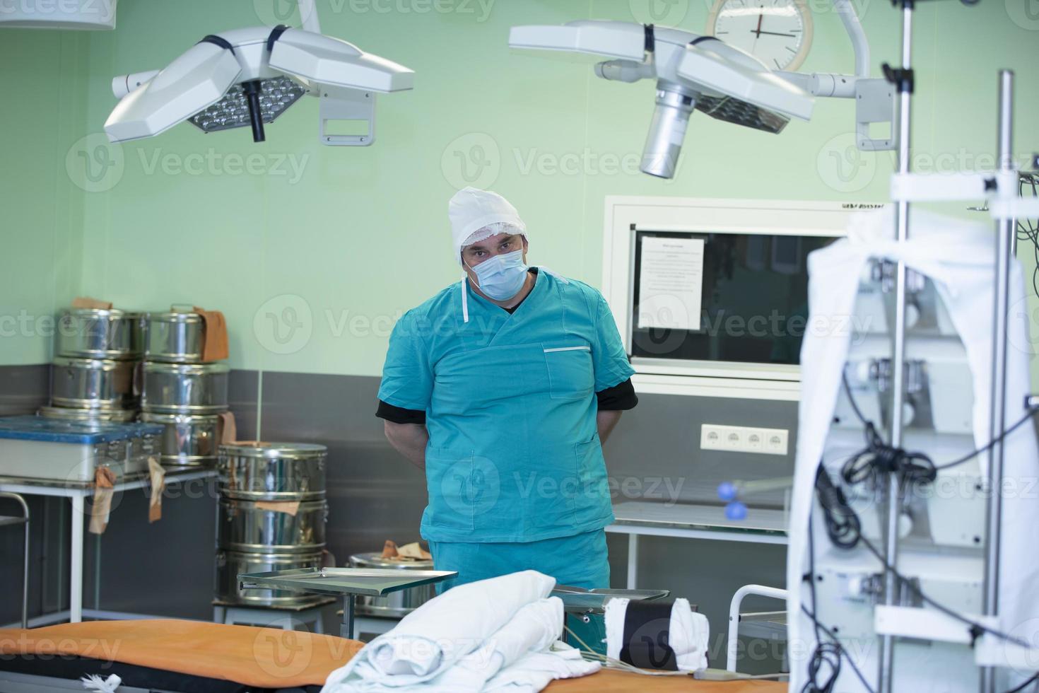 A doctor in a surgical suit stands in the operating room among the equipment.Portrait of surgeon in the operating room photo