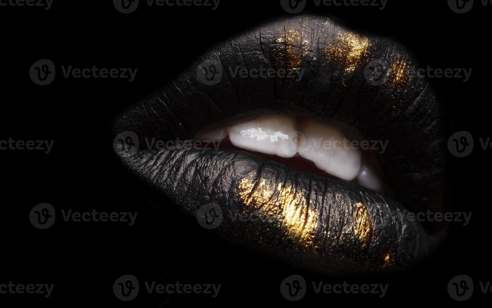 Golden and black lipstick close-up. Metallic gold lips.Sexy lips, lip paint Black and gold. Metal lipstick close-up. photo