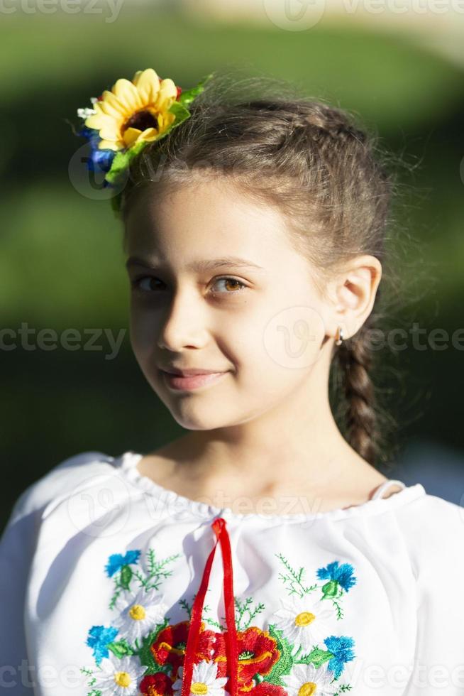 una niña ucraniana y bielorrusa con una camisa bordada en un fondo de verano. foto