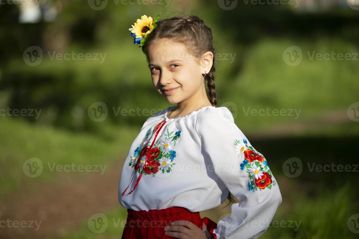 A little Ukrainian and Belarusian girl in an embroidered shirt on a summer background. photo