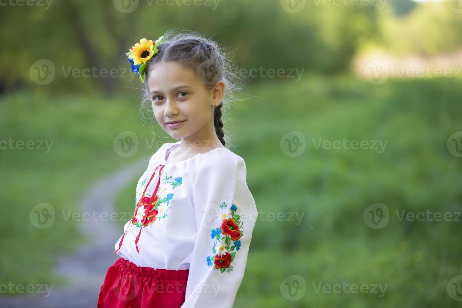 una niña ucraniana y bielorrusa con una camisa bordada en un fondo de verano. foto