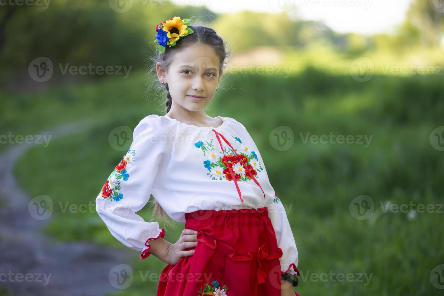 A little Ukrainian and Belarusian girl in an embroidered shirt on a summer background. photo