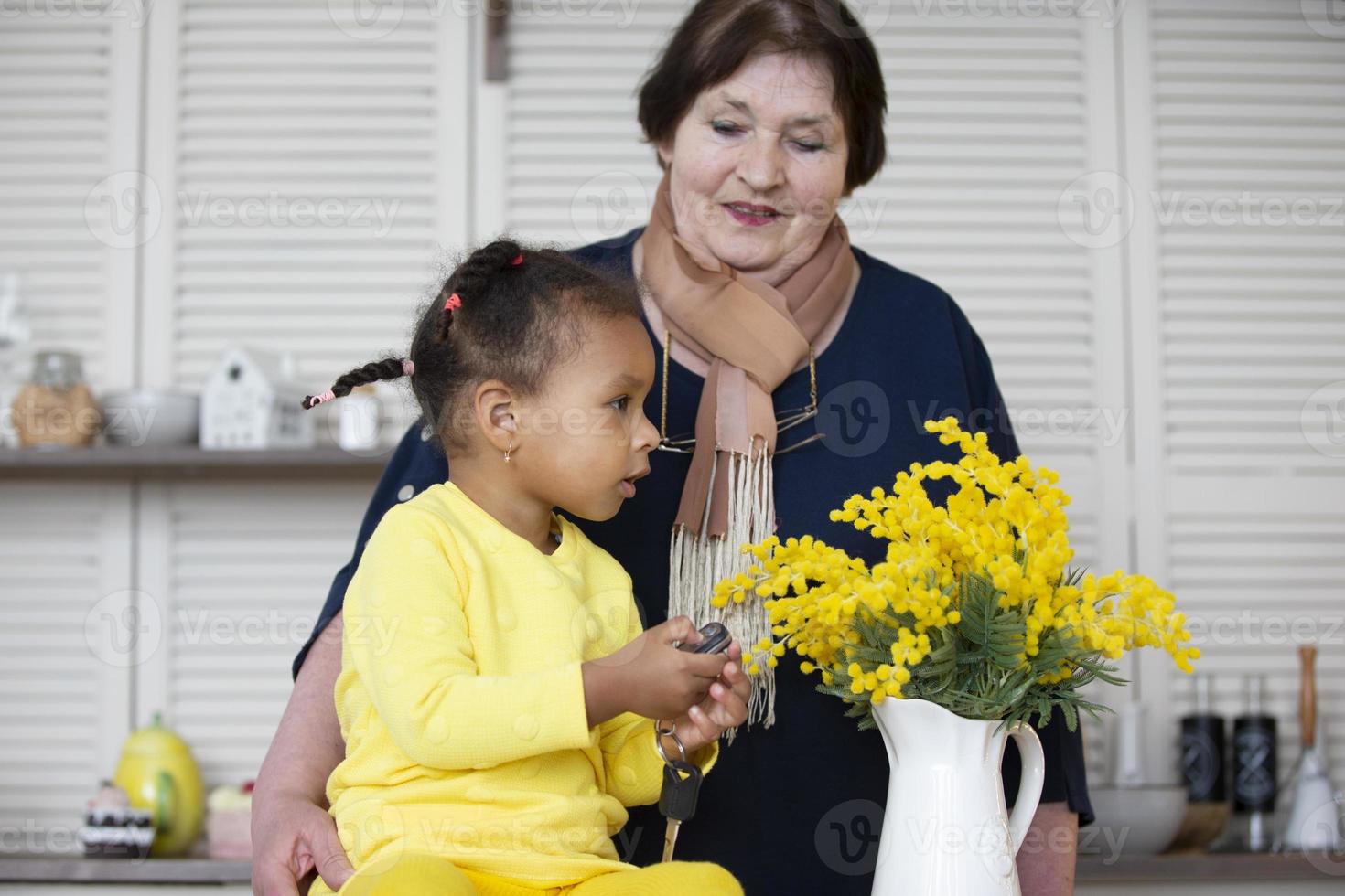 abuela y nieta de diferentes razas. la abuela de piel clara juega con la nieta de piel oscura. foto