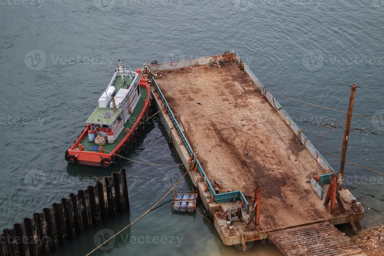 remolcador y barcaza o embarcación de fondo plano estacionados al lado del mar listos para cargar. foto