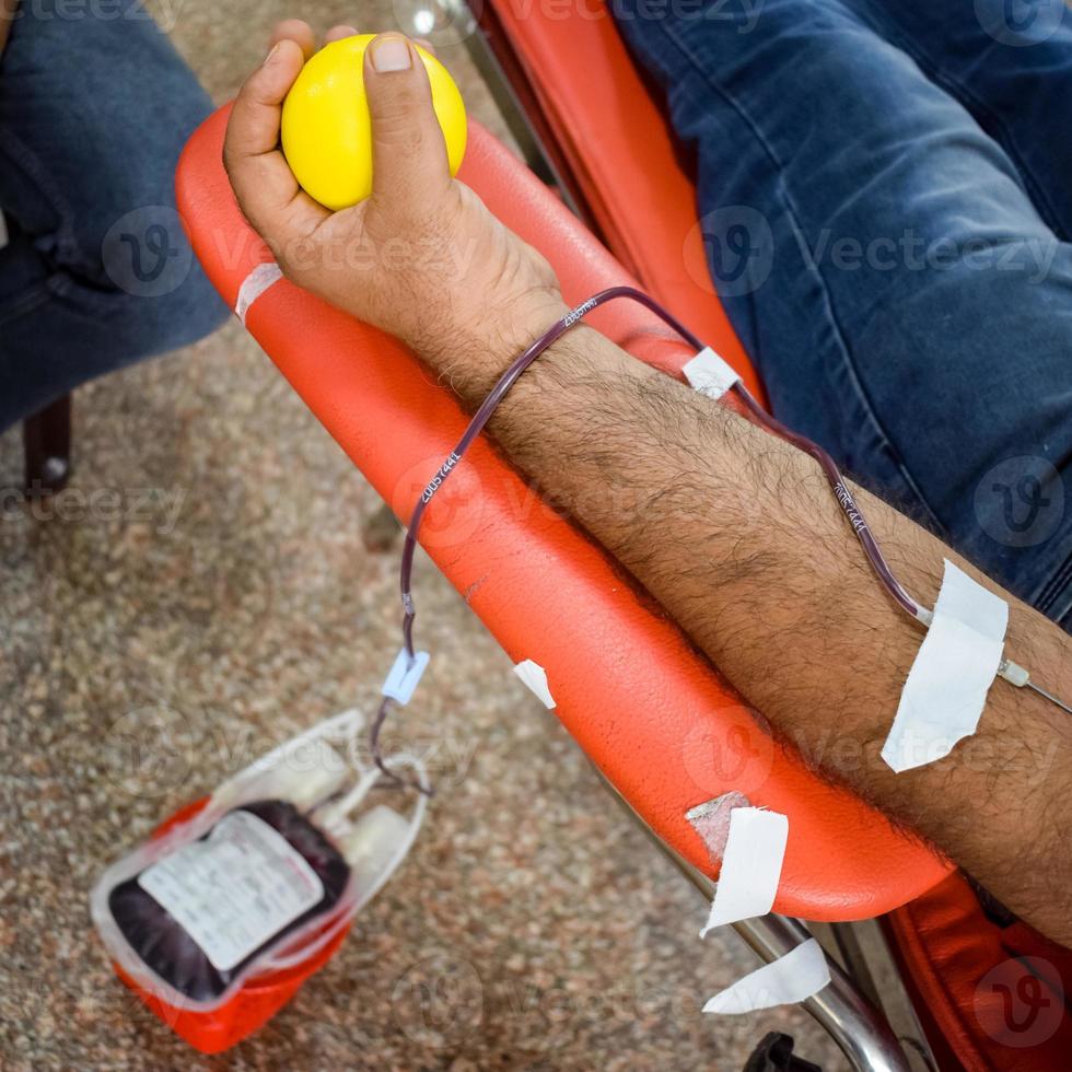 donante de sangre en el campamento de donación de sangre sostenido con una pelota hinchable en la mano en el templo balaji, vivek vihar, delhi, india, imagen para el día mundial del donante de sangre el 14 de junio de cada año, campamento de donación de sangre foto