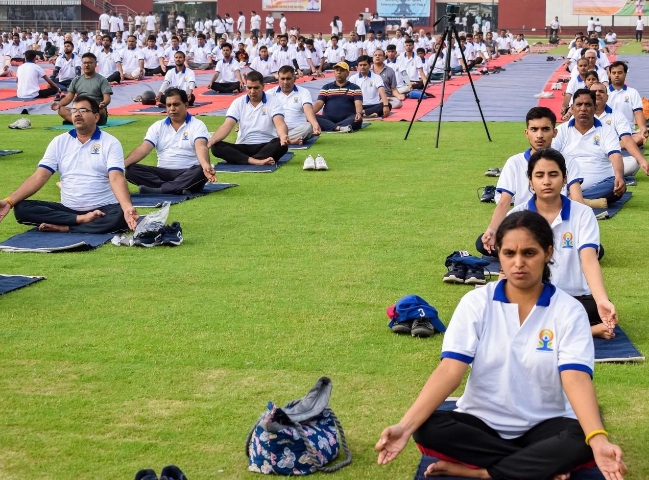 New Delhi, India, June 21 2022 - Group Yoga exercise session for people at Yamuna Sports Complex in Delhi on International Yoga Day, Big group of adults attending yoga class in cricket stadium photo