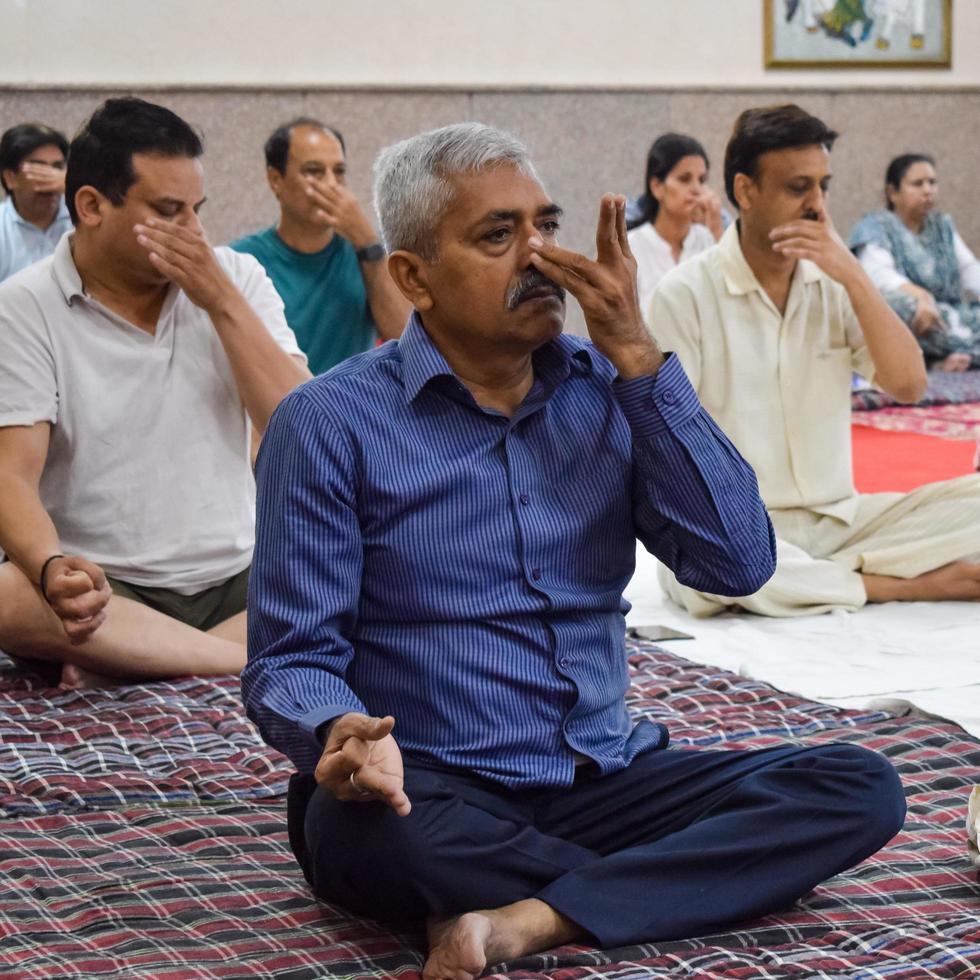 New Delhi, India, June 19 2022 -Group Yoga exercise session for people of different age groups in Balaji Temple, Vivek Vihar, International Yoga Day, Big group of adults attending yoga class in temple photo