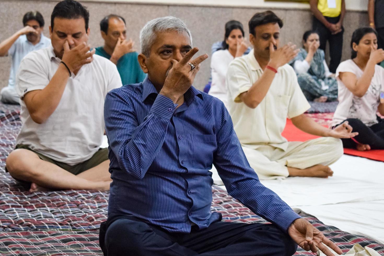 New Delhi, India, June 19 2022 -Group Yoga exercise session for people of different age groups in Balaji Temple, Vivek Vihar, International Yoga Day, Big group of adults attending yoga class in temple photo